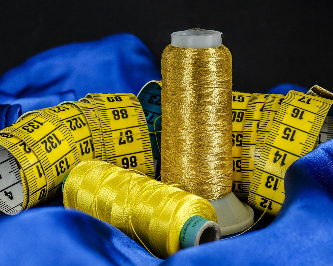 Золотые нитки и сантиметр на голубой ткани 