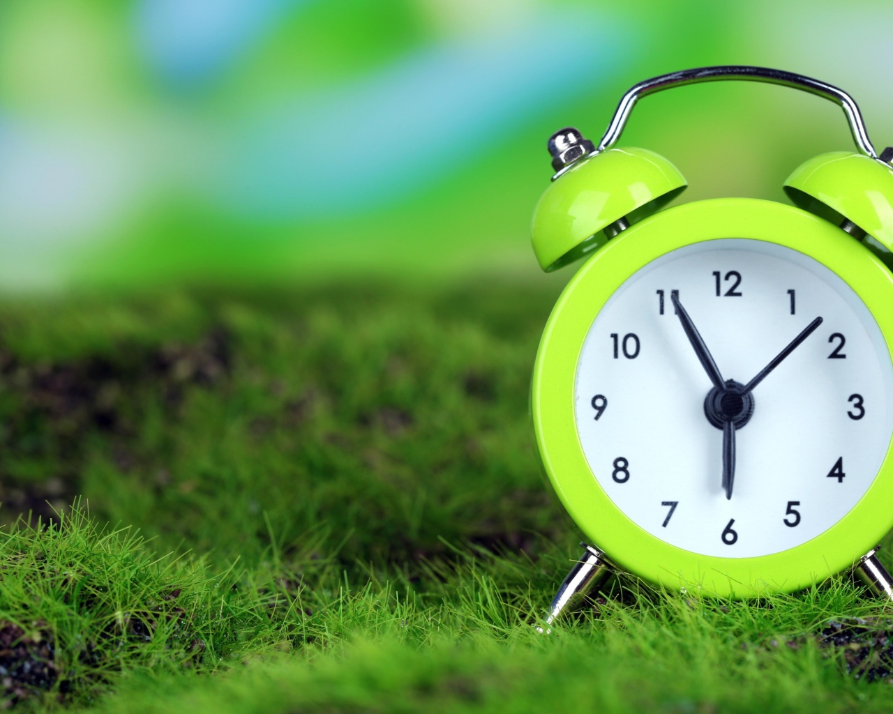 Зеленый будильник стоит на траве
