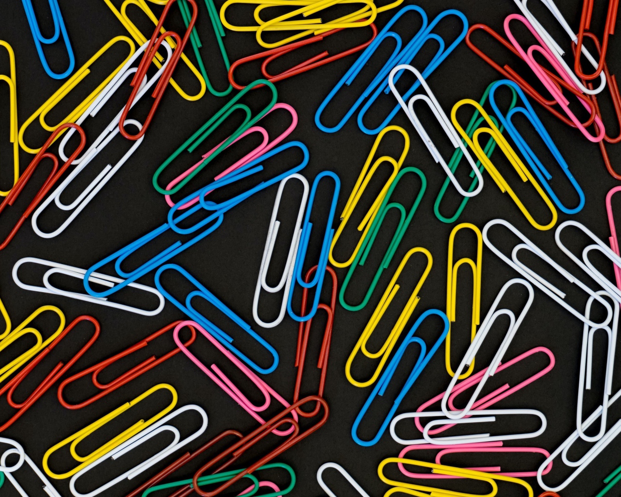 Many multi-colored paper clips on a black background