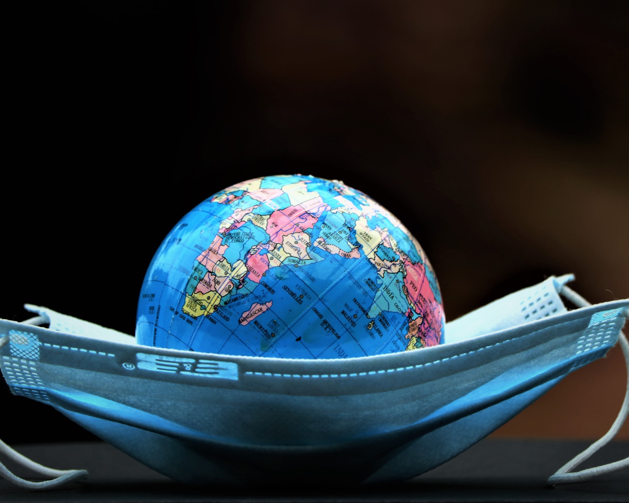 Медицинская маска и глобус на черном фоне