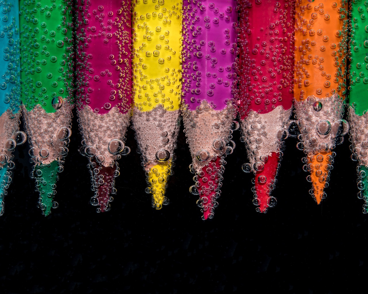 Разноцветные карандаши в воде на черном фоне