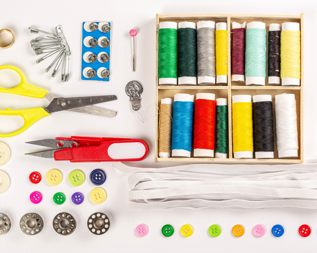 Разноцветые нитки и предметы для шитья на белом фоне 