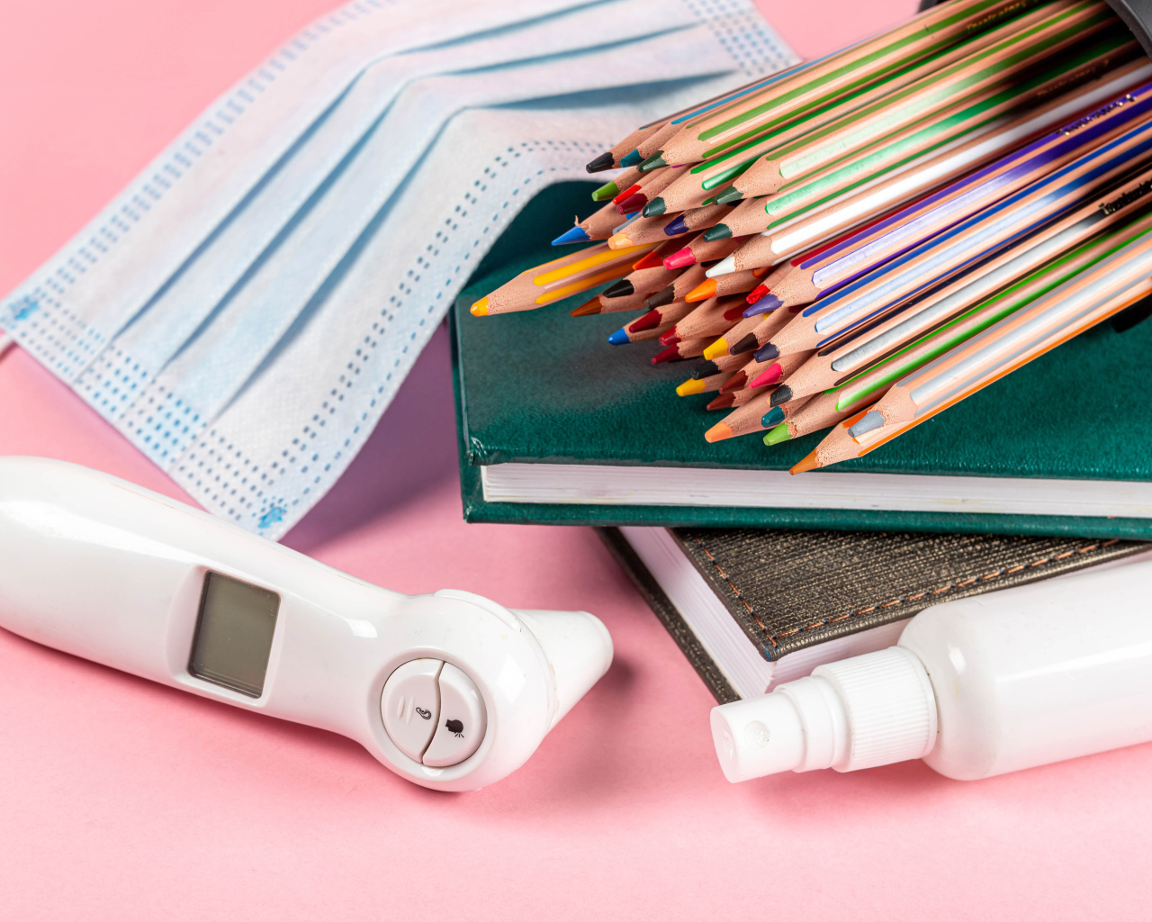 Карандаши, градусник, маска и блокнот на розовом фоне 