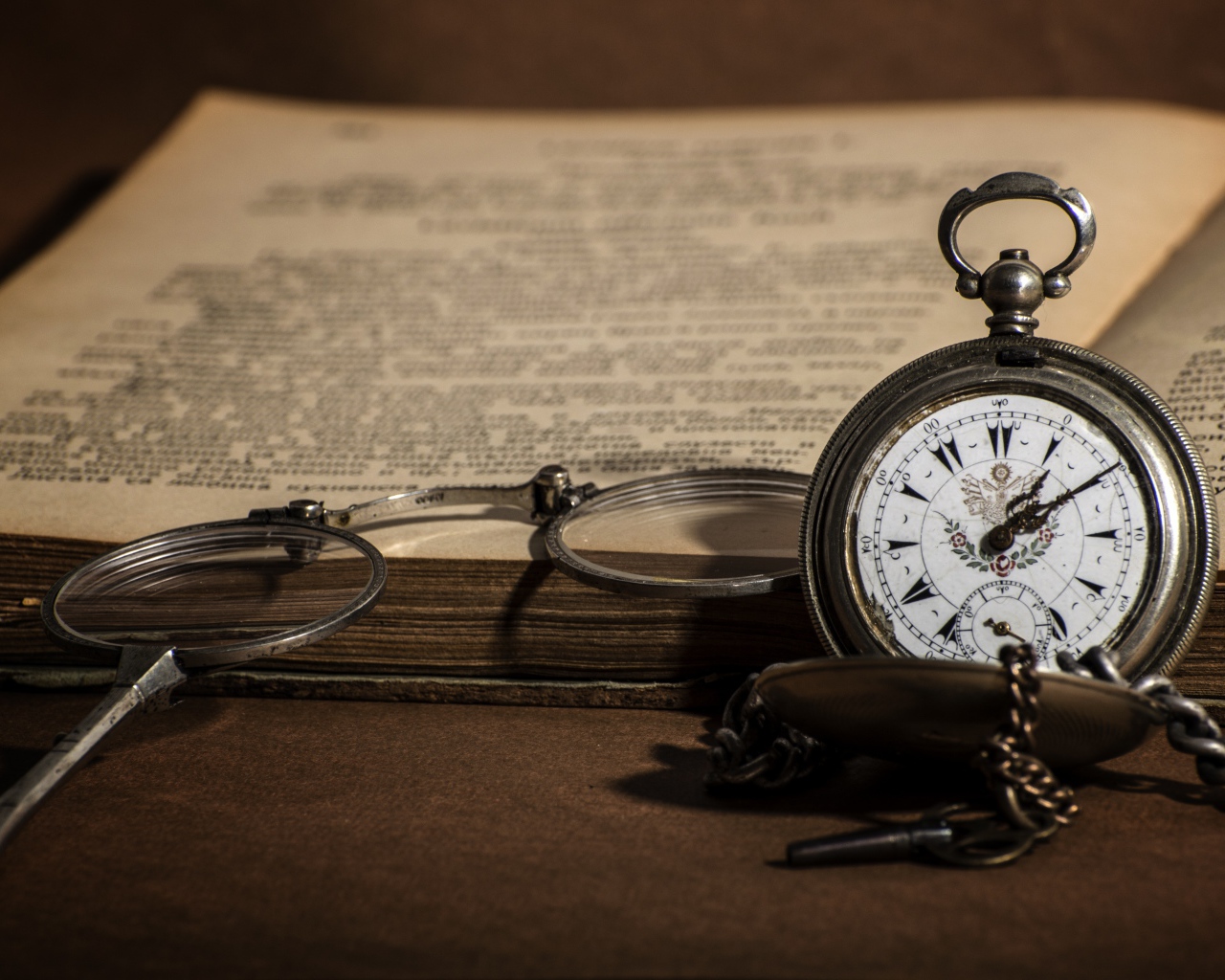 Карманные часы на цепочке на столе с книгой 
