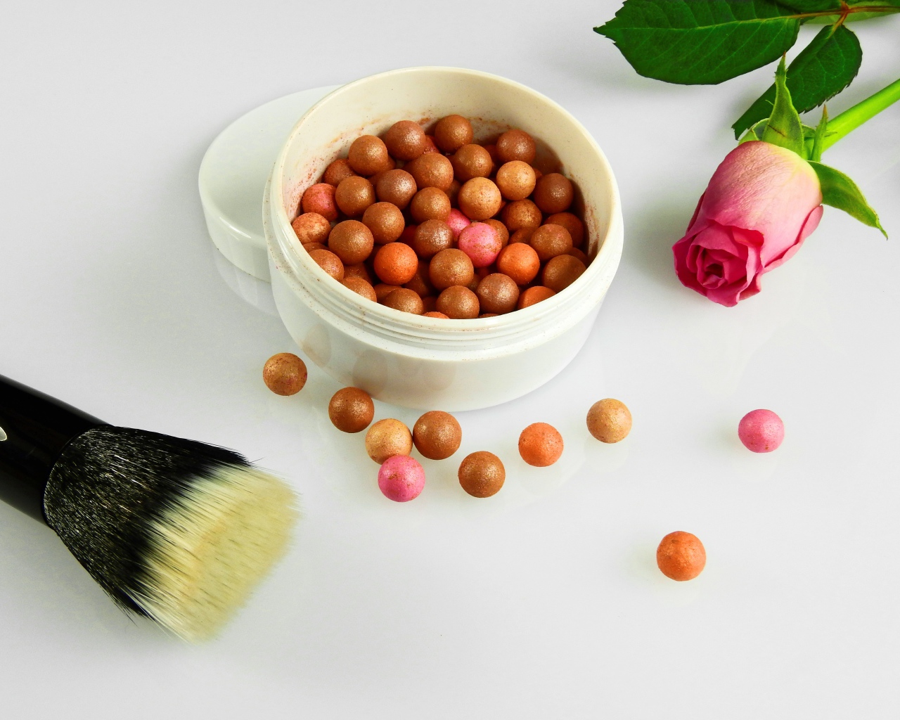 Шариковая пудра на белом фоне с кистью и розой