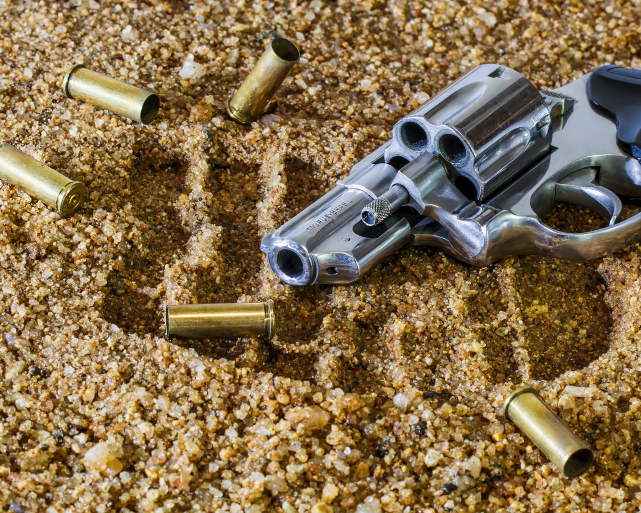 Револьвер с гильзами лежат на песке