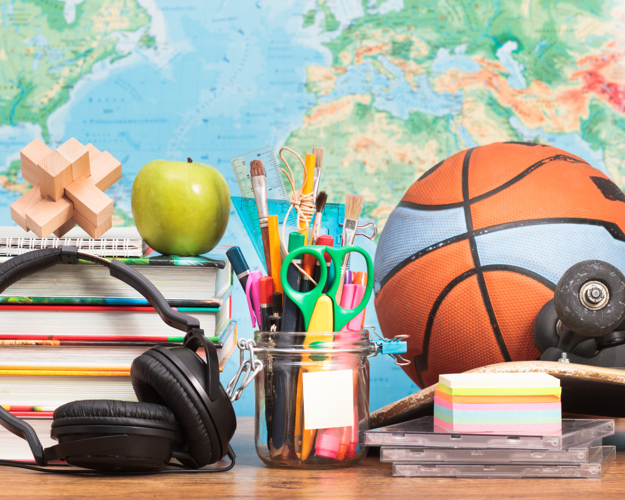 Школьные принадлежности на столе с наушниками и мячом 