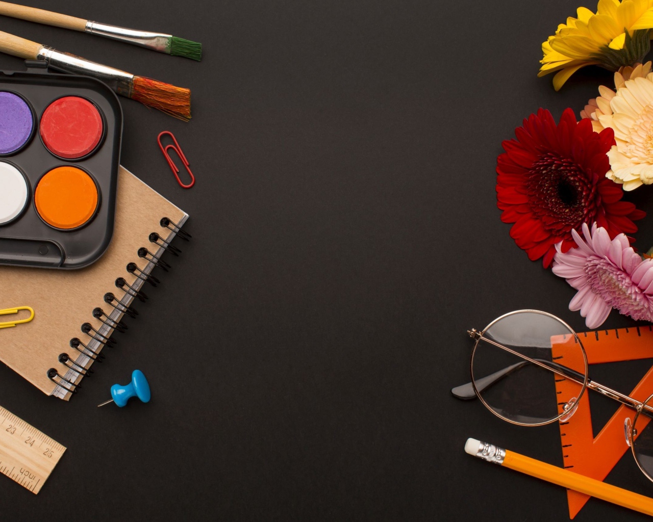 Канцелярские предметы, очки и герберы на черном фоне 