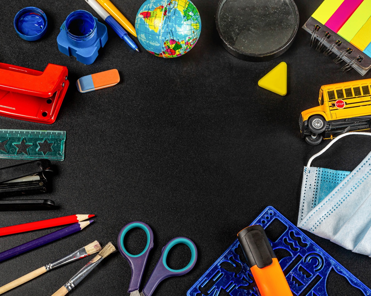 Канцелярские предметы, игрушки и маска на черном столе 