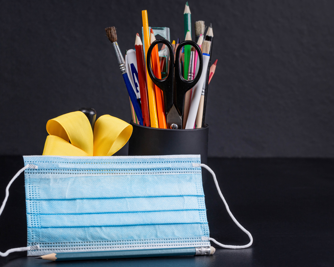 Канцелярские предметы на столе с медицинской маской