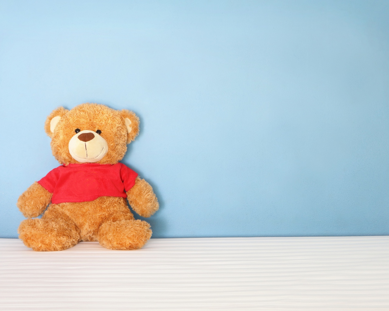 Плюшевый мишка на фоне голубой стены