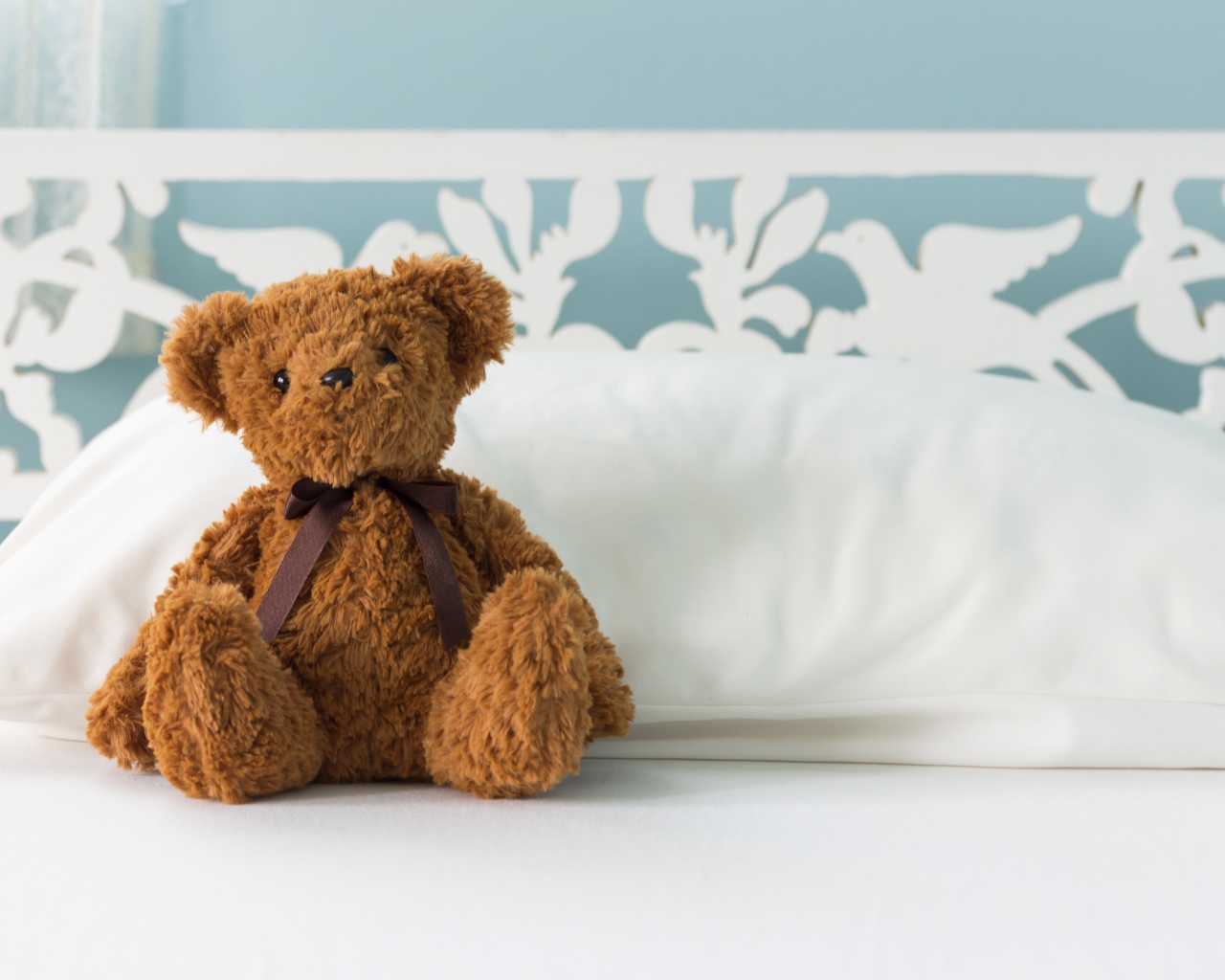 Игрушечный медвежонок сидит на белой постели