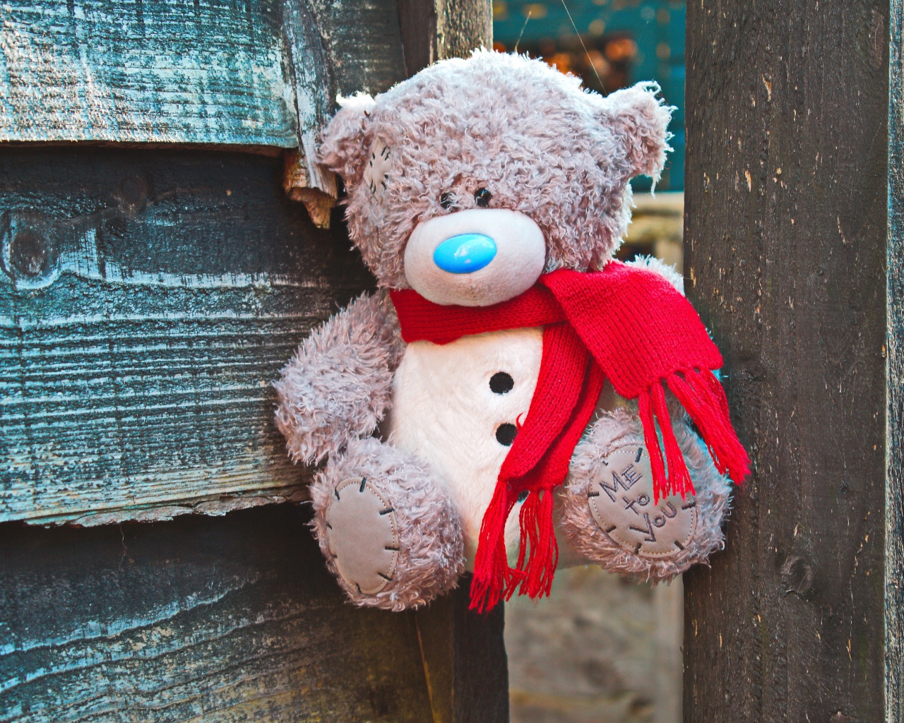 Медвежонок Тедди с красным бантом на заборе 