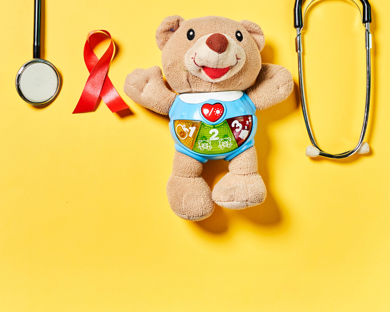 Игрушечный медвежонок с фонендоскопом на желтом фоне 