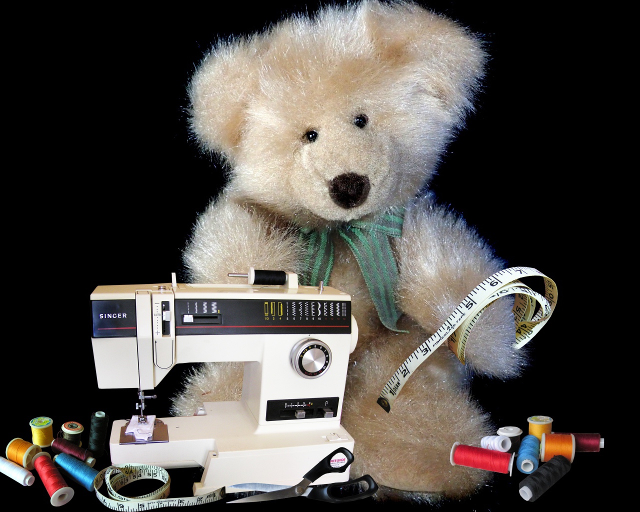 Игрушечный медвежонок со швейной машинкой на черном фоне 