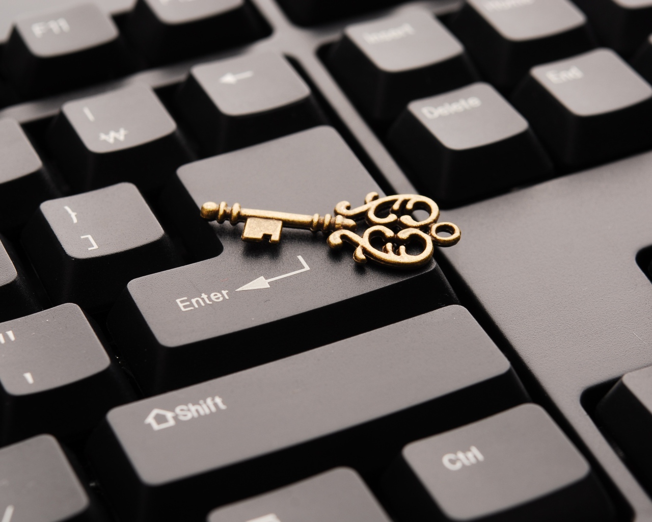 Золотой ключ лежит на черной клавиатуре