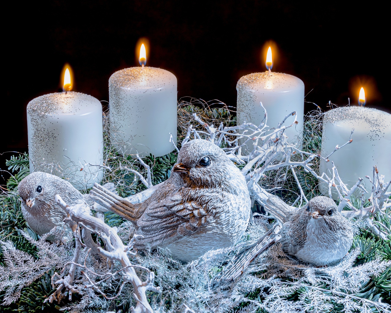 Три зажженные свечи со статуэтками птицами 