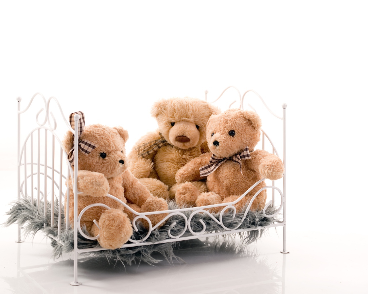 Три игрушечных медведя на кровати на белом фоне