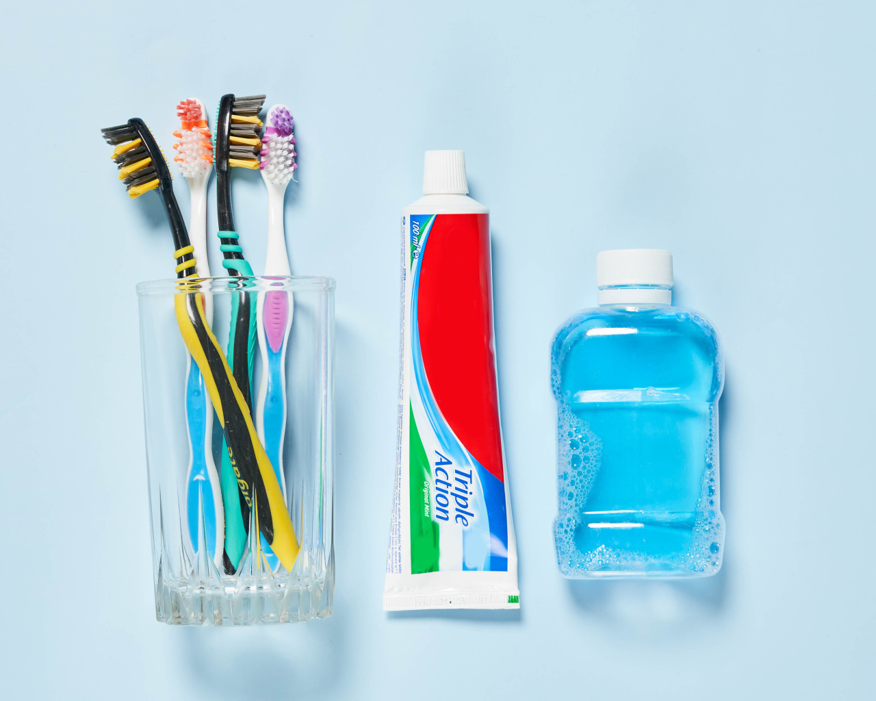 Зубная паста с щетками и ополаскивателем на сером фоне 