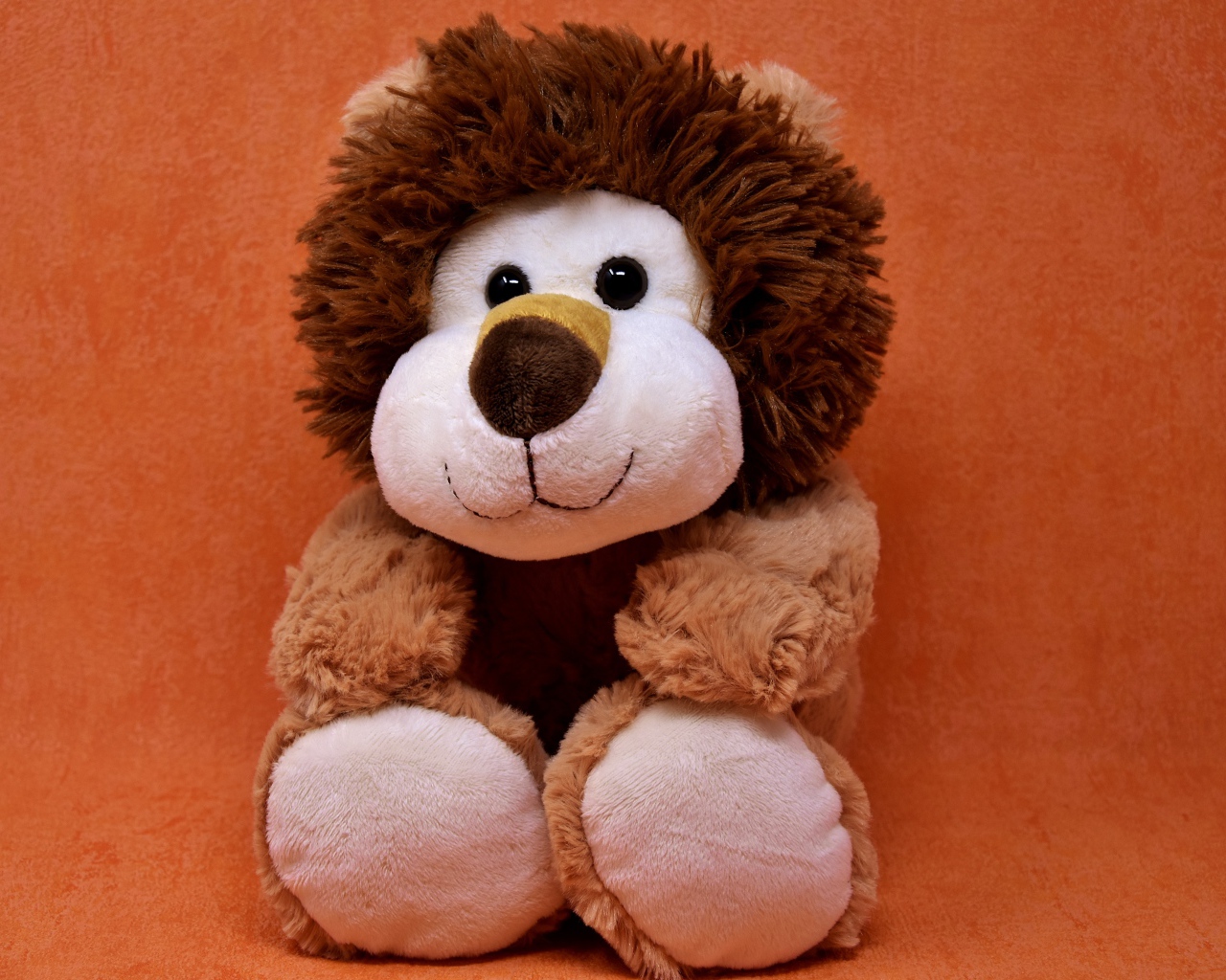 Игрушечный лев на фоне стены