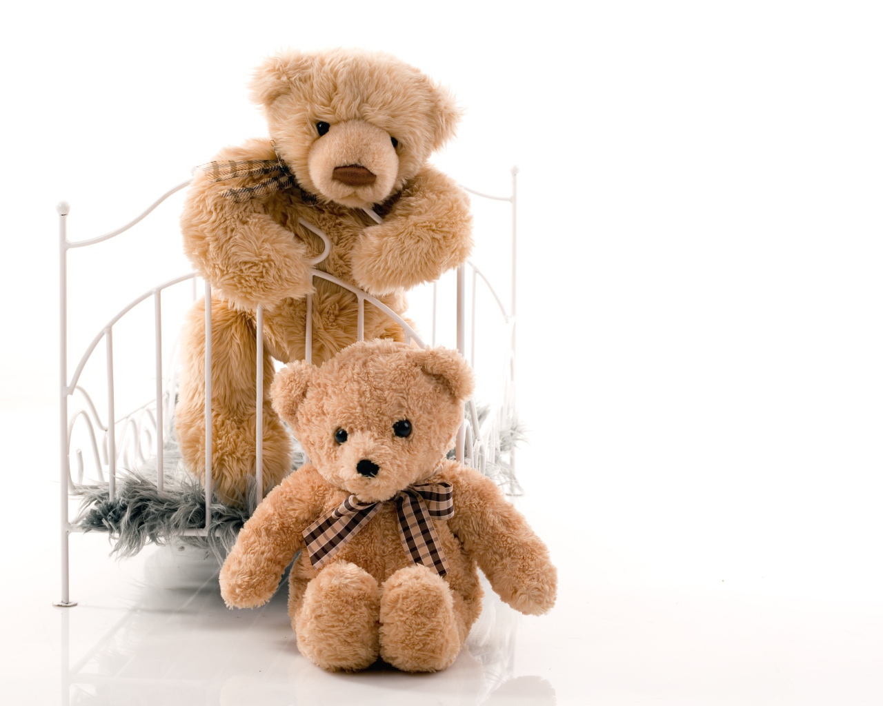 Два игрушечных медведя с кроватью на белом фоне 