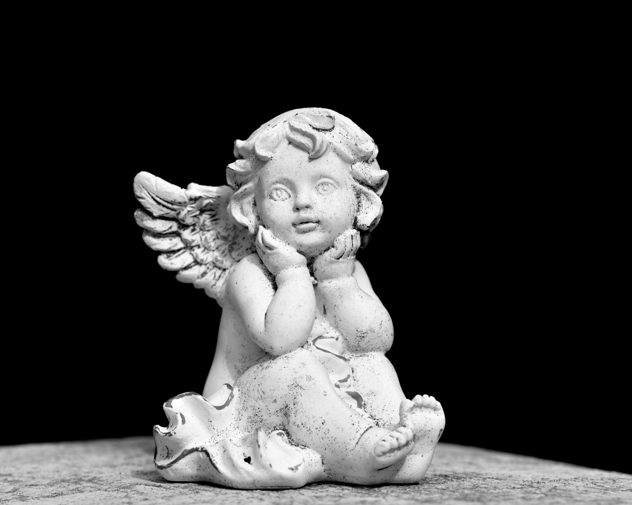 Белая статуэтка ангел на черном фоне