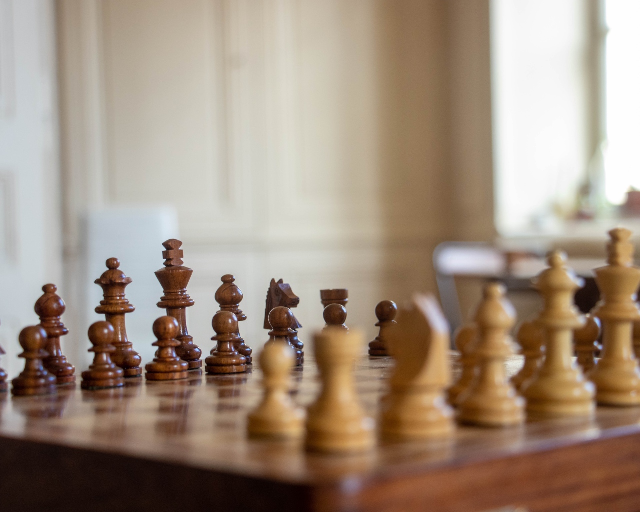 Деревянные шахматы на доске у окна