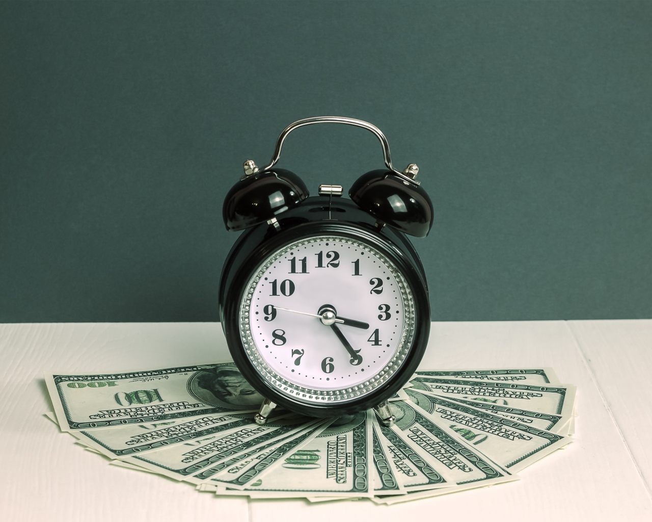 Черный будильник и доллары на столе