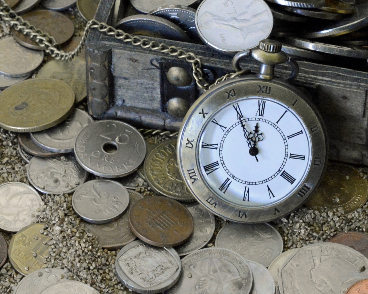 Много монет и карманные часы на песке