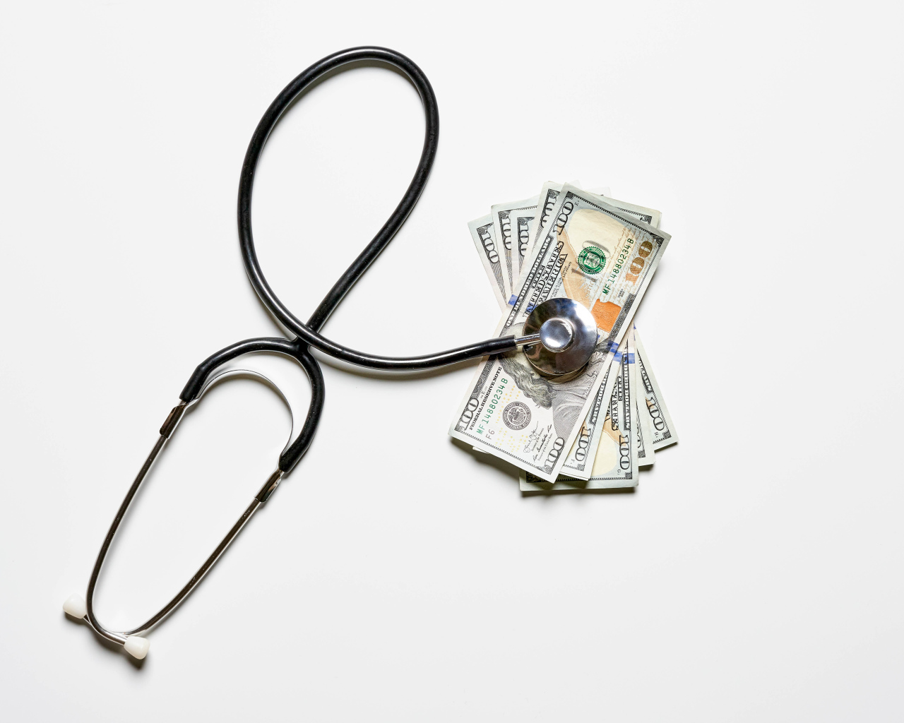 Фонендоскоп с долларами на белом фоне