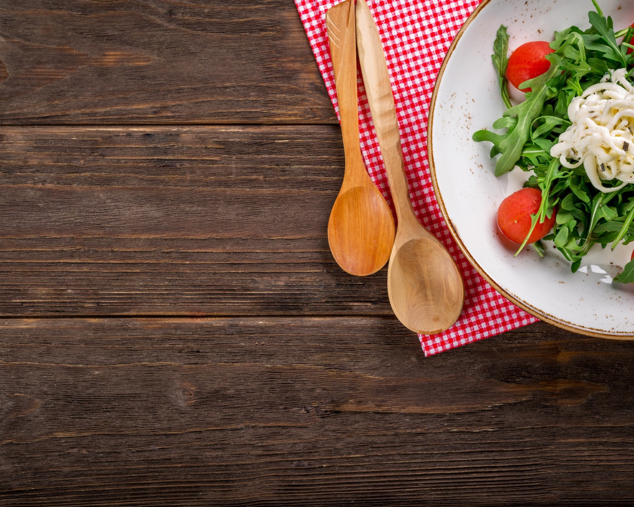 Руккола с помидорами на тарелке с ложками 