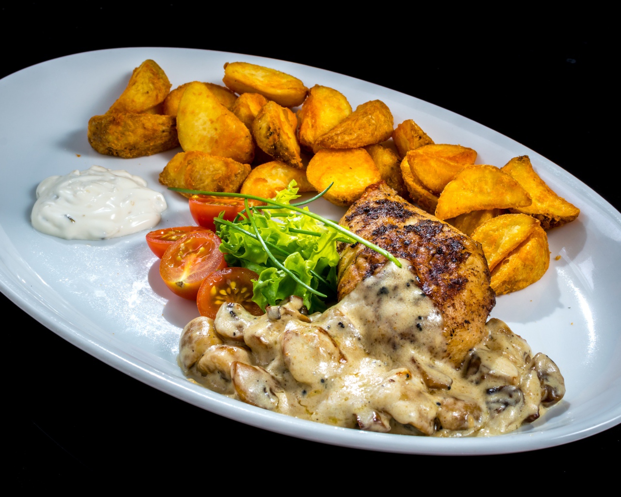 Запеченный картофель с грибами, мясом и овощами на тарелке