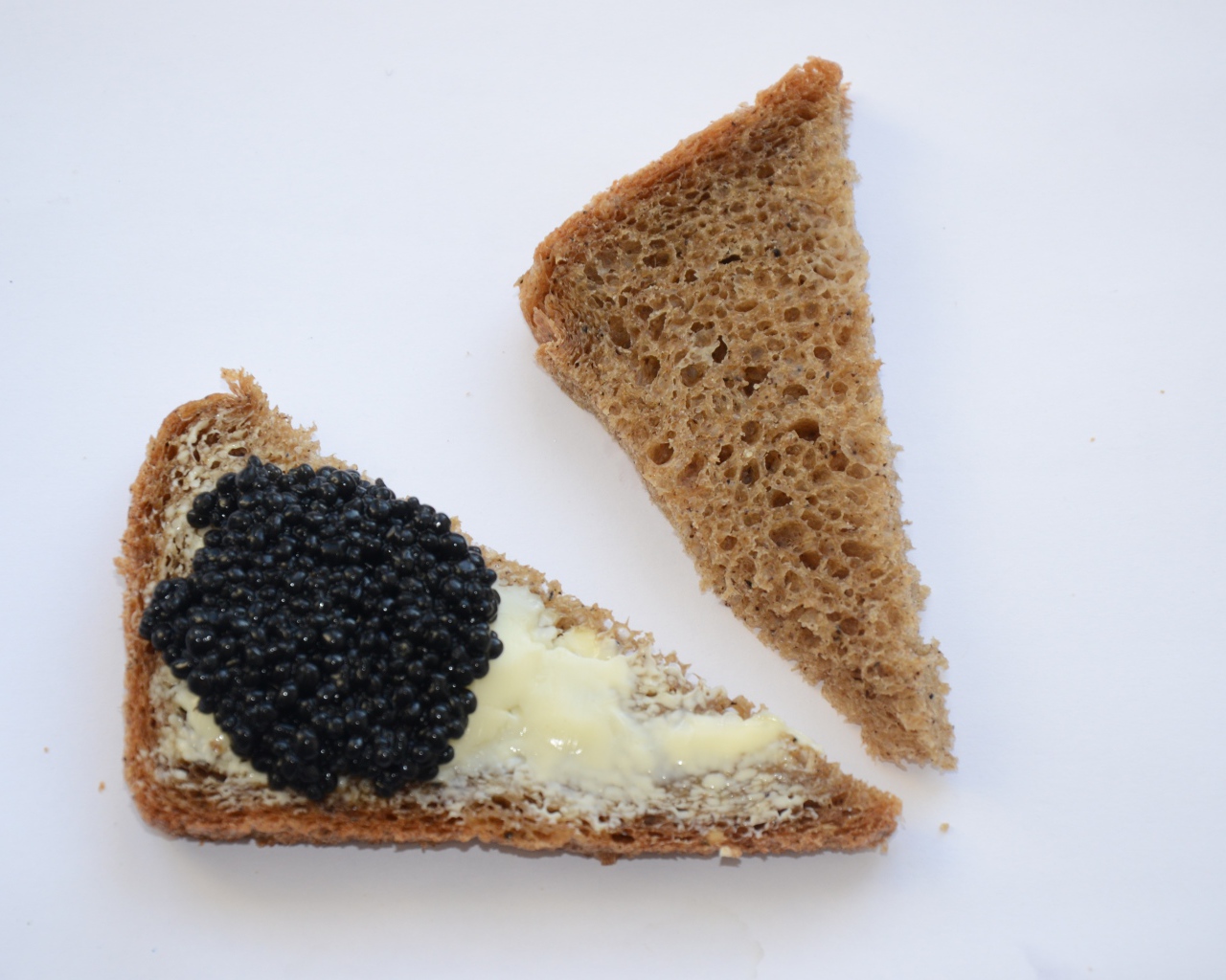 Бутерброды из черного хлеба с черной икрой на сером фоне