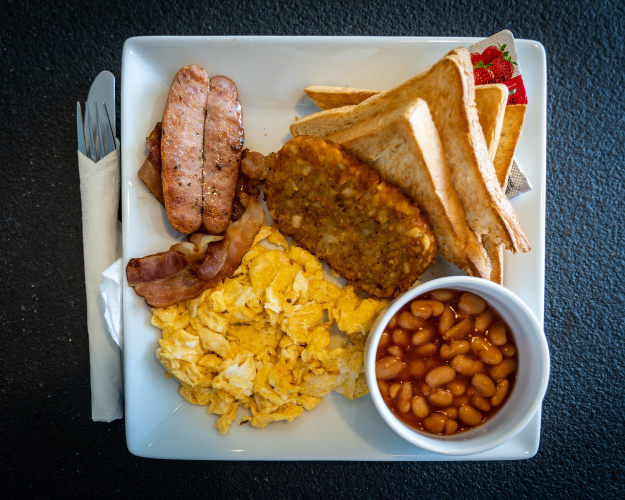 Завтрак на белой тарелке на черном столе 