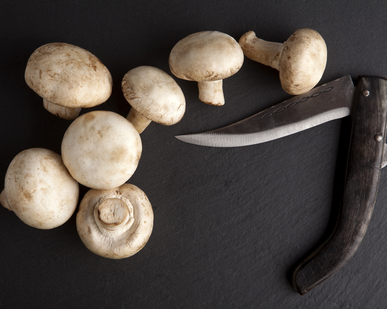Шампиньоны на сером столе с ножом