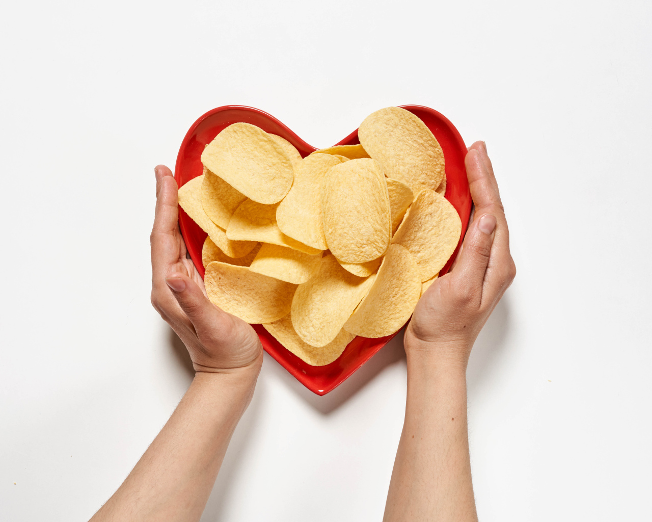 Чипсы в красной тарелке на белом фоне