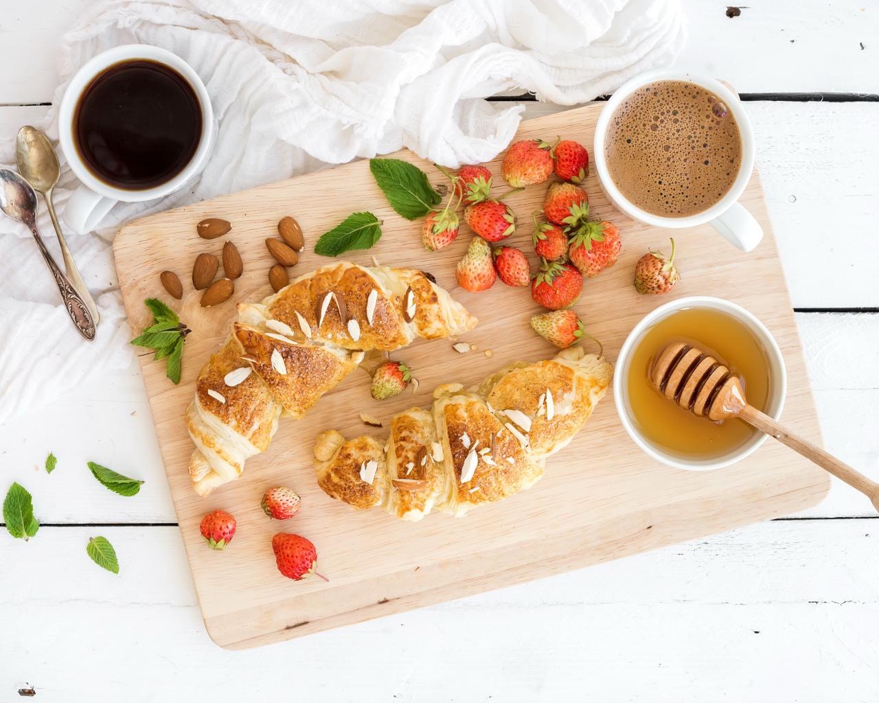 Круассаны на столе с орехами, клубникой и кофе