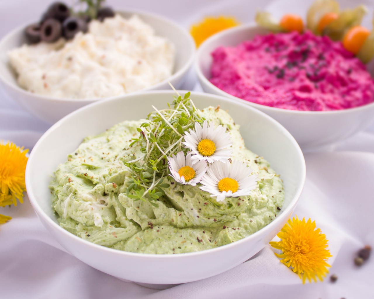 Вкусные салаты в белых мисках на столе с цветами