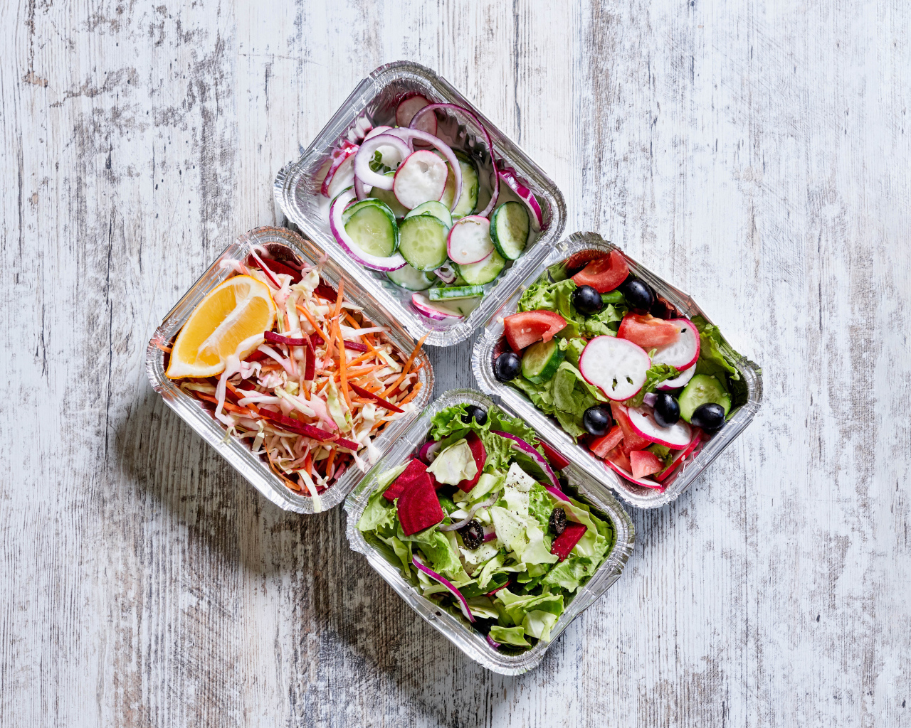 Разные овощные салаты в тарелках на сером столе 