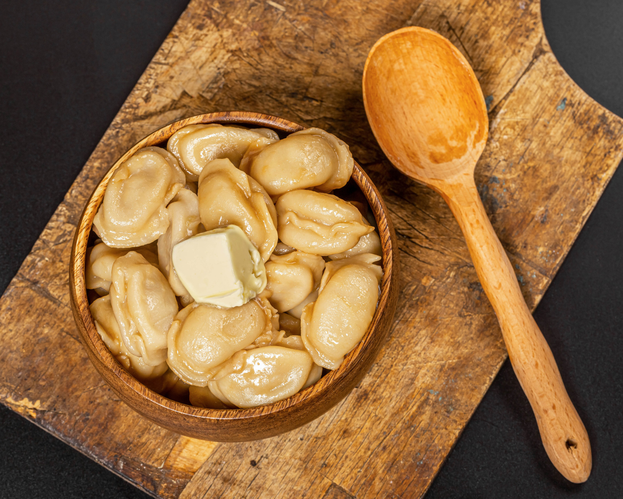 Пельмени в деревянной миске с маслом