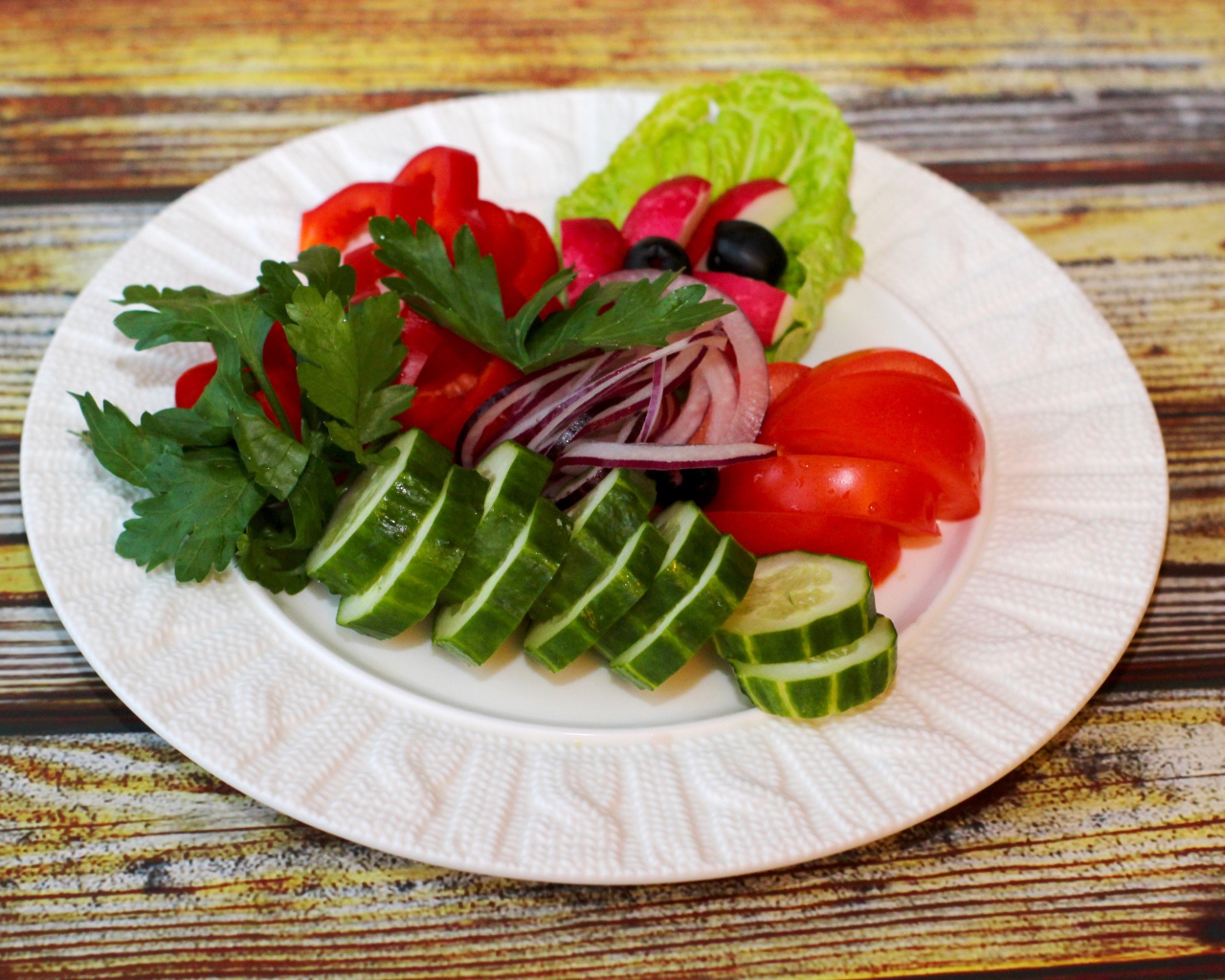 Свежие овощи на белой тарелке на деревянном фоне