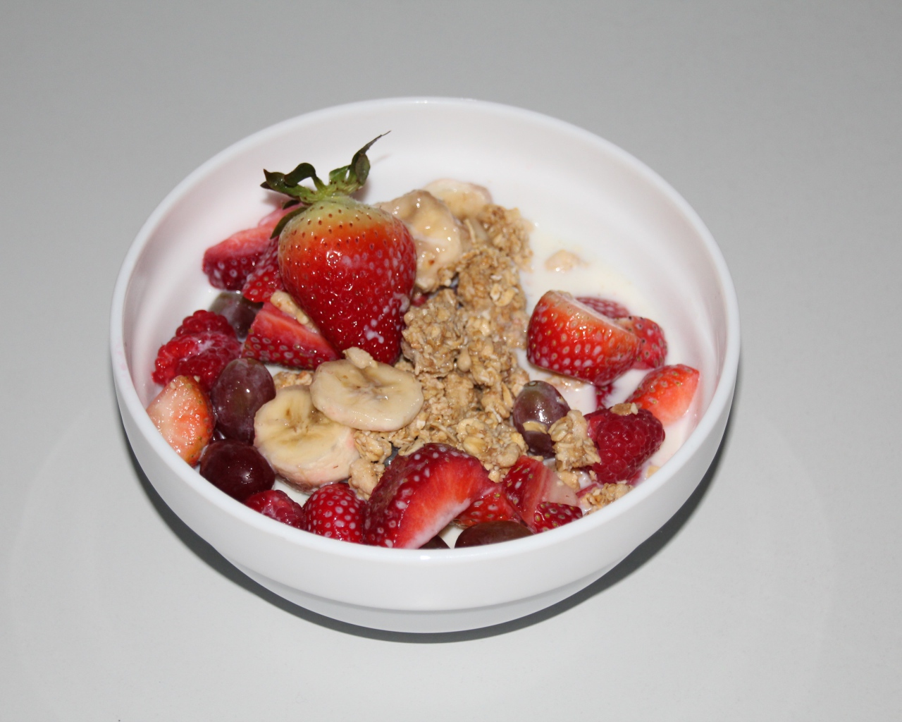 Мюсли с молоком и ягодами на сером столе