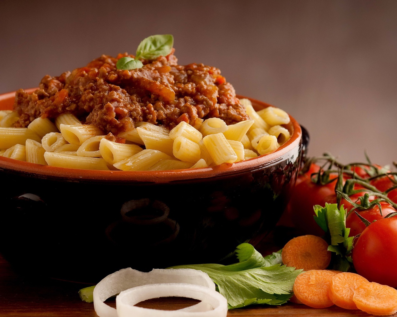 Макароны в миске с фаршем на столе с помидорами