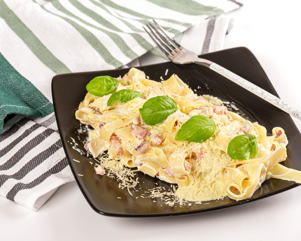 Макароны на тарелке с тертым сыром и кусочками мяса