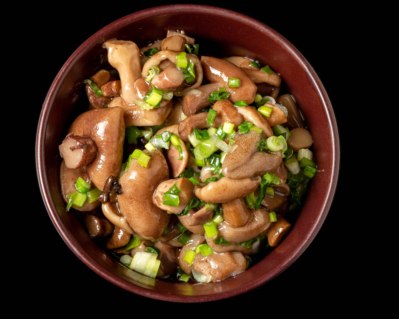 Маринованные маслята с зеленью в тарелке