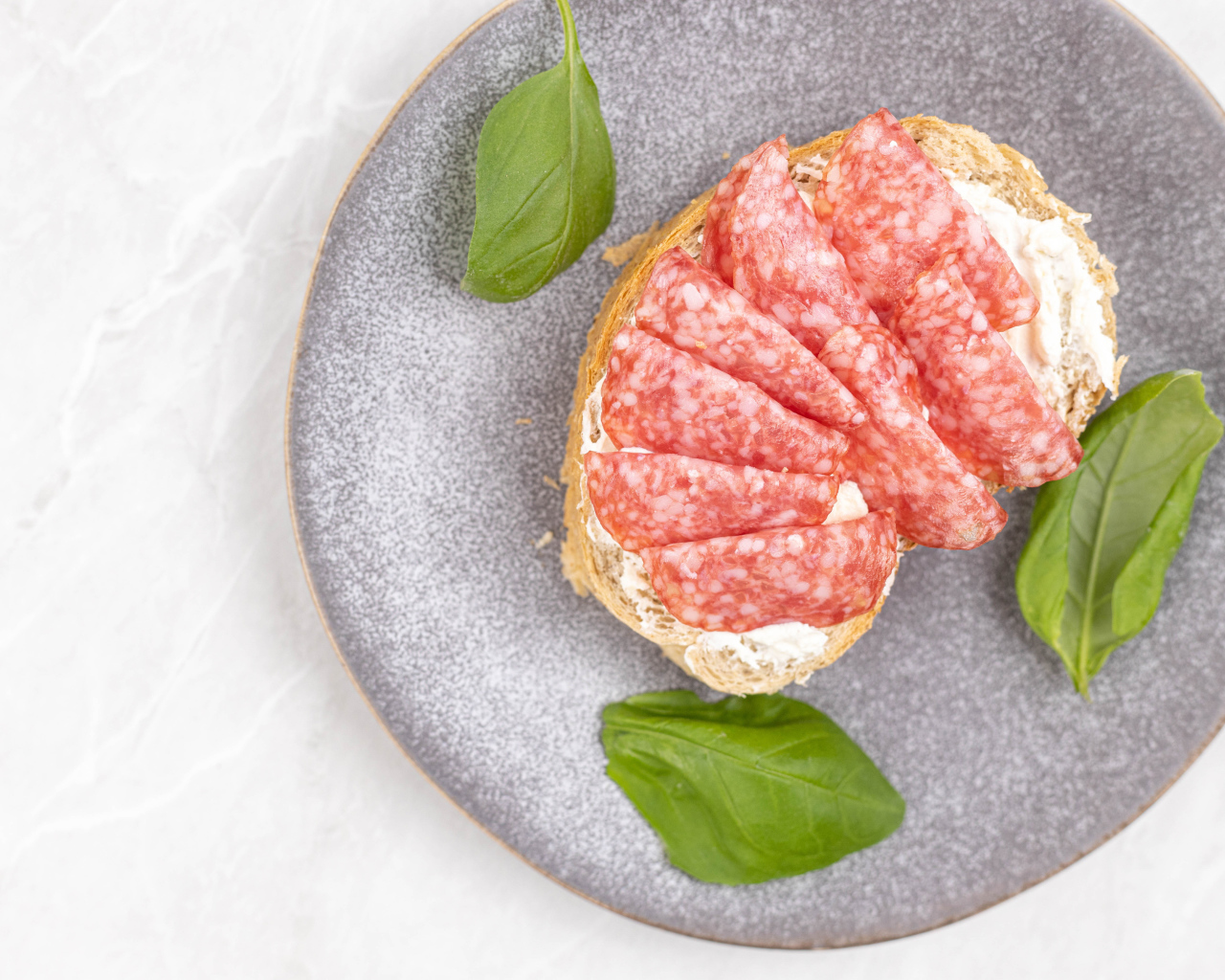 Бутерброд с маслом и колбасой на тарелке