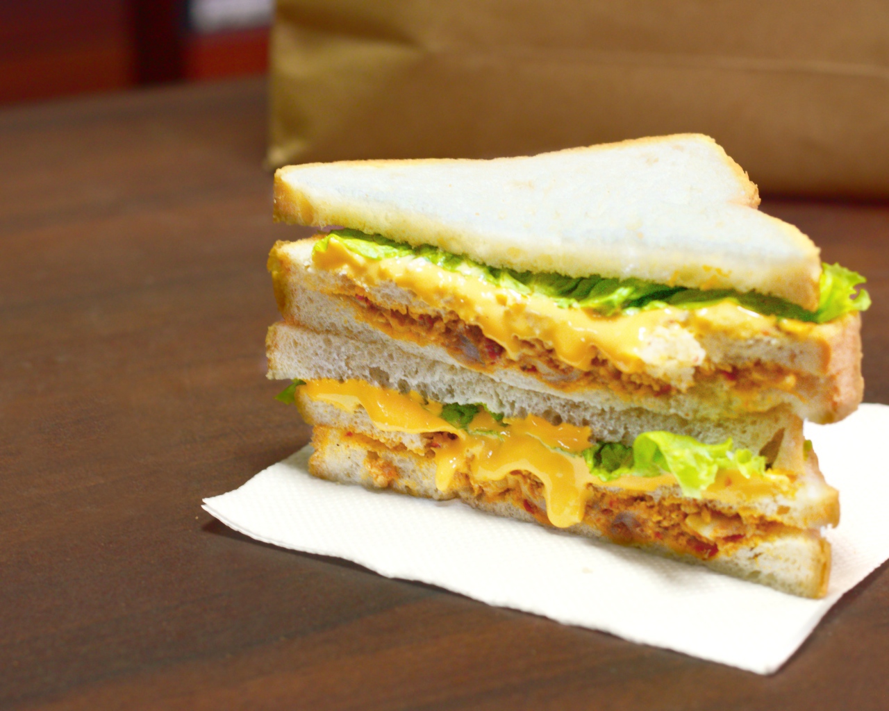 Сэндвич с сыром и листьями салата на столе