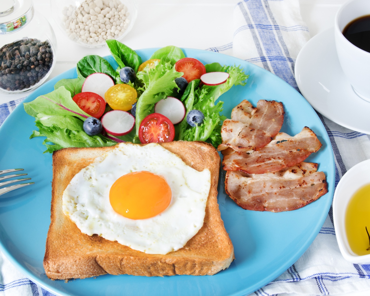 Яичница с хлебом на тарелке с салатом и беконом 
