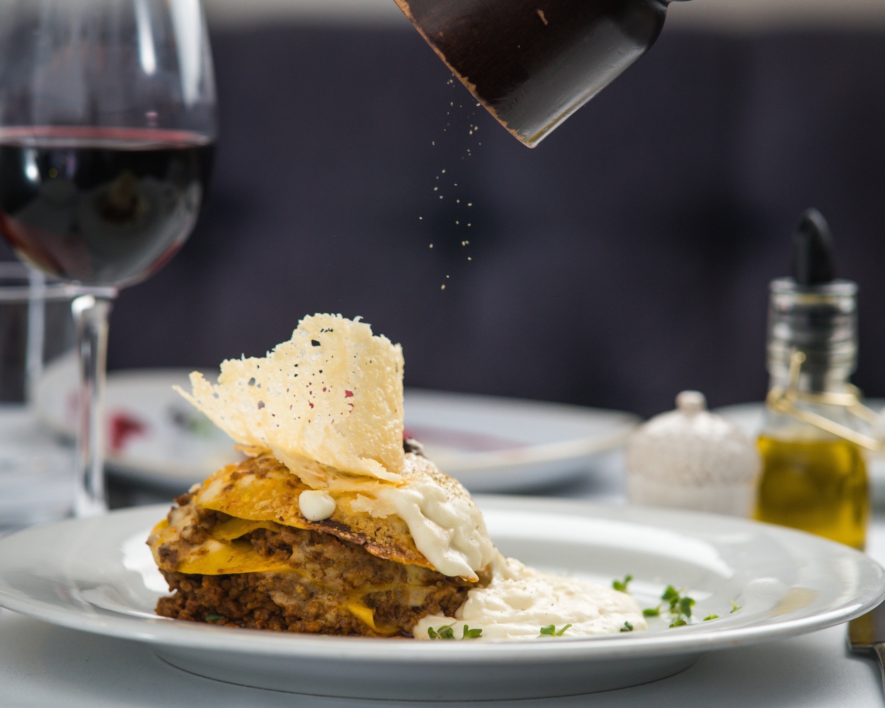 Кусок лазаньи посыпают перцем 