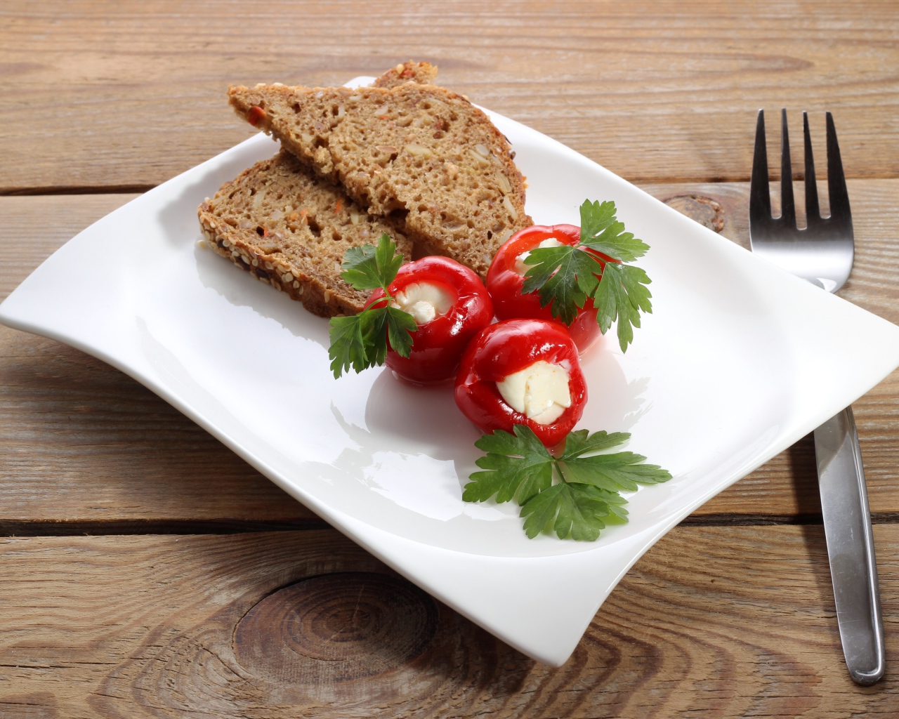 Фаршированный перец на большой белой тарелке с хлебом